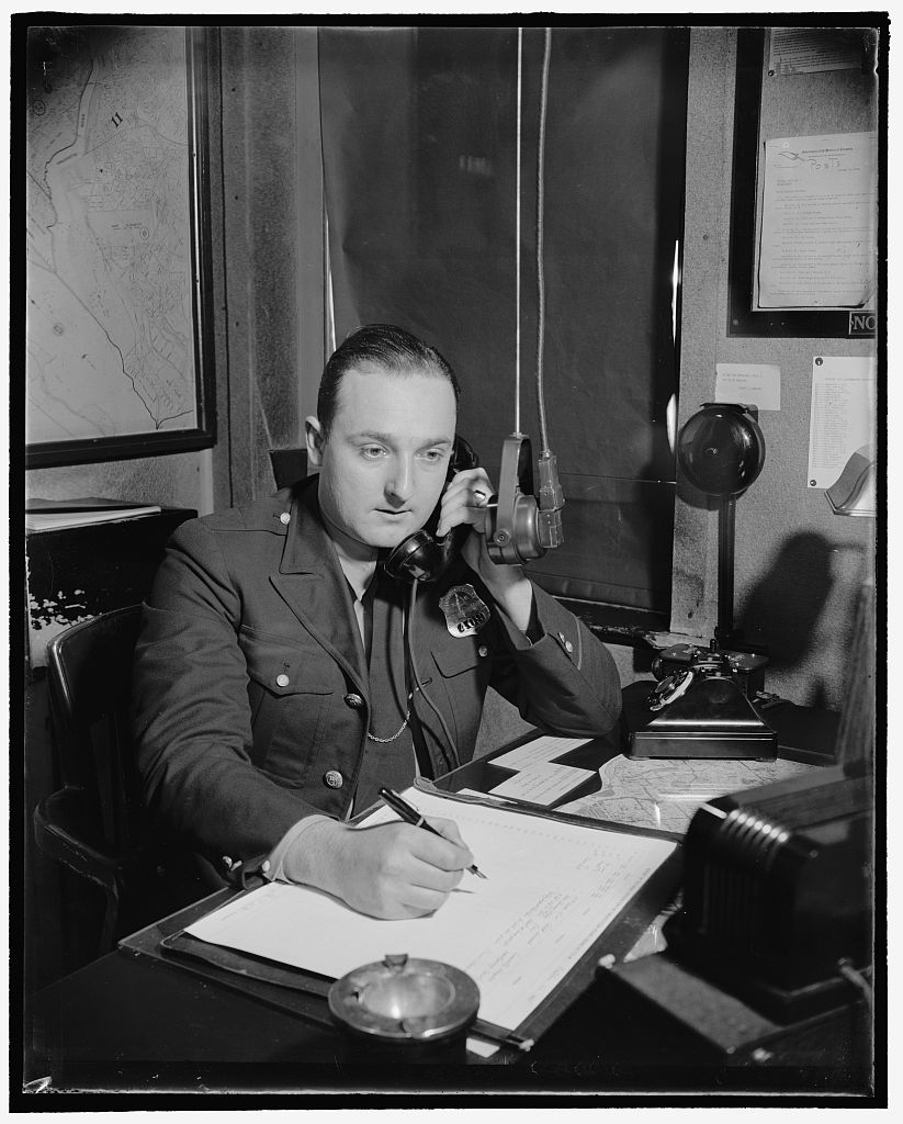 Radio dispatcher taking a telephone call before repeating it into a microphone.