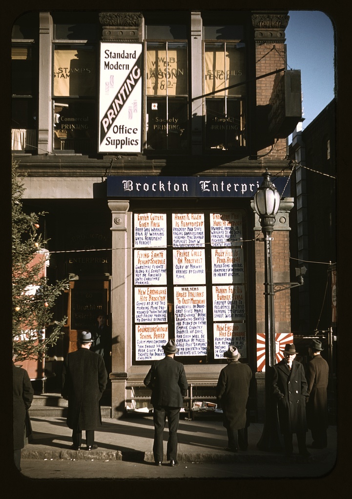 Men reading newspaper headlines posted outside the Brockton Enterprise office.